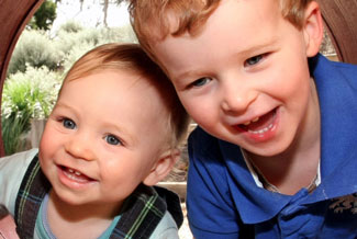 Two young boys laughing and hugging outdoors